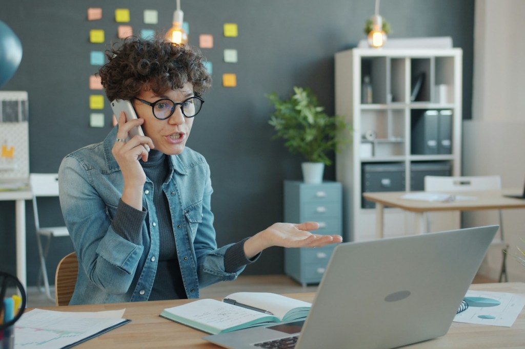 Stressed-woman-speaking-on-a-phone-in-an-office