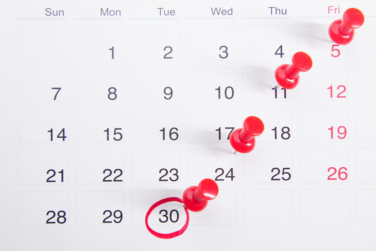 White wall calendar with red pins and a red circle marketing dates 
